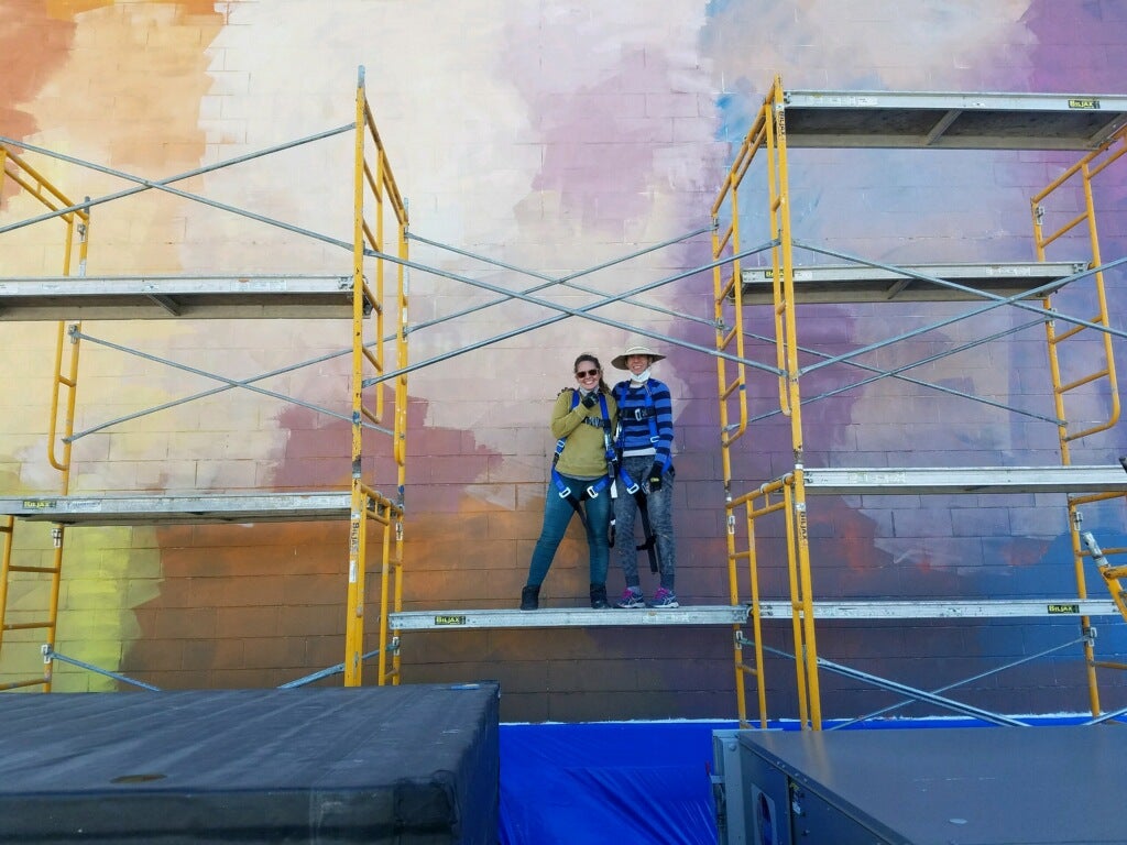 DIA studio staff posing in front of a section of the mural