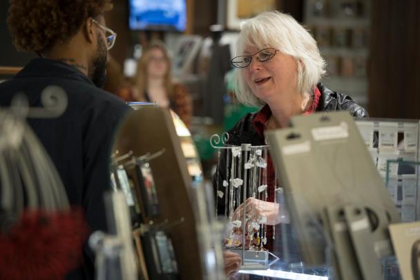 A DIA museum shop employee shows a guest some necklaces.