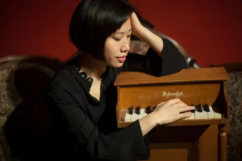 Phyllis Chen pictured with her arms around a tiny piano.