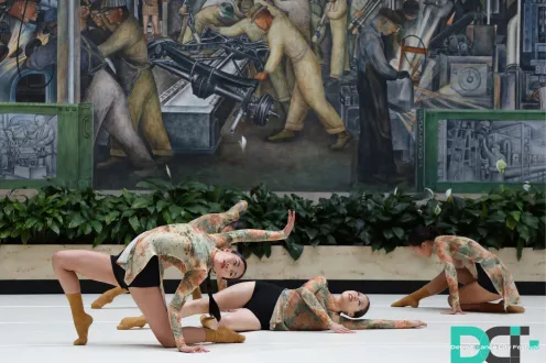 Dancers in various poses on the ground in the DIA's Rivera Court