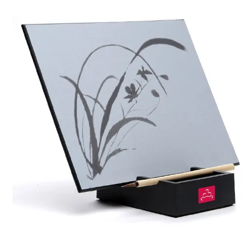 A Buddha board, featuring a gray background and a dark gray grass and floral design drawn on it.
